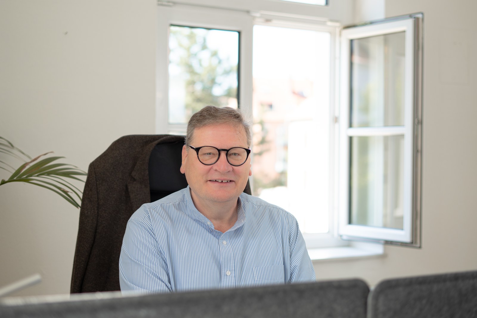 Ralf Hartleb am Schreibtisch — im hellen Büro